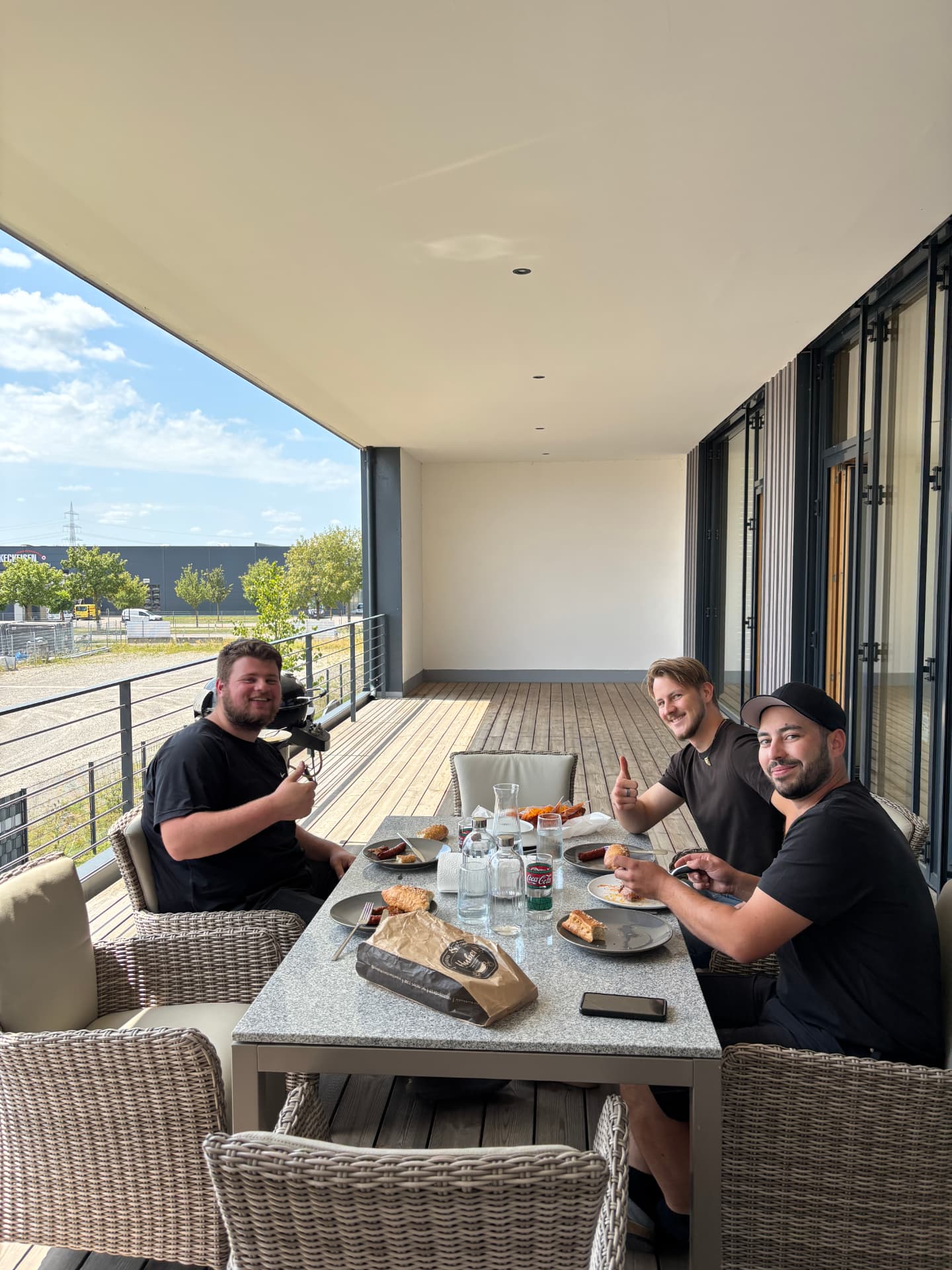 Drei Kollegen bei der Mittagspause auf der Büroterrasse